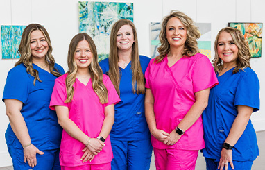 Coppell pediatric dental team members smiling in blue scrubs