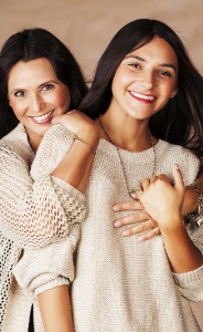 Mother and daughter smiling and wearing matching beige sweaters