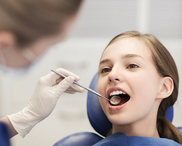 A dental hygienist looking at a young girl’s smile during a regular appointment