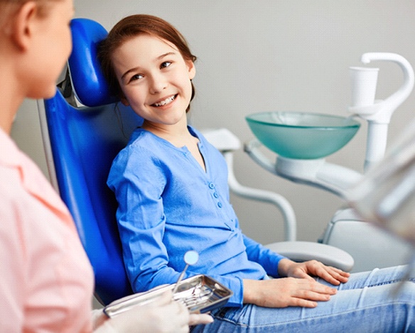 A little girl smiling while listening to her dentist in Coppell discuss fluoride treatments
