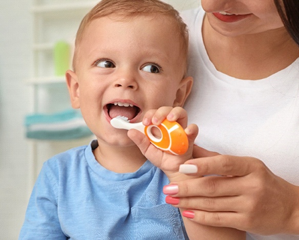 A little boy brushing his baby teeth in Coppell Texas while his mother observes