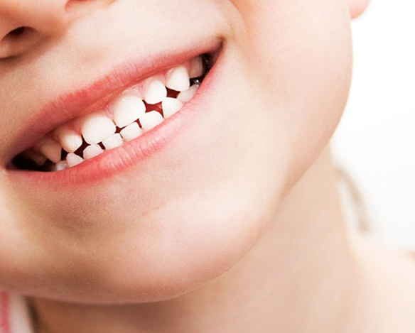 An up-close view of a young child’s smile, complete with both the top and bottom row of baby teeth