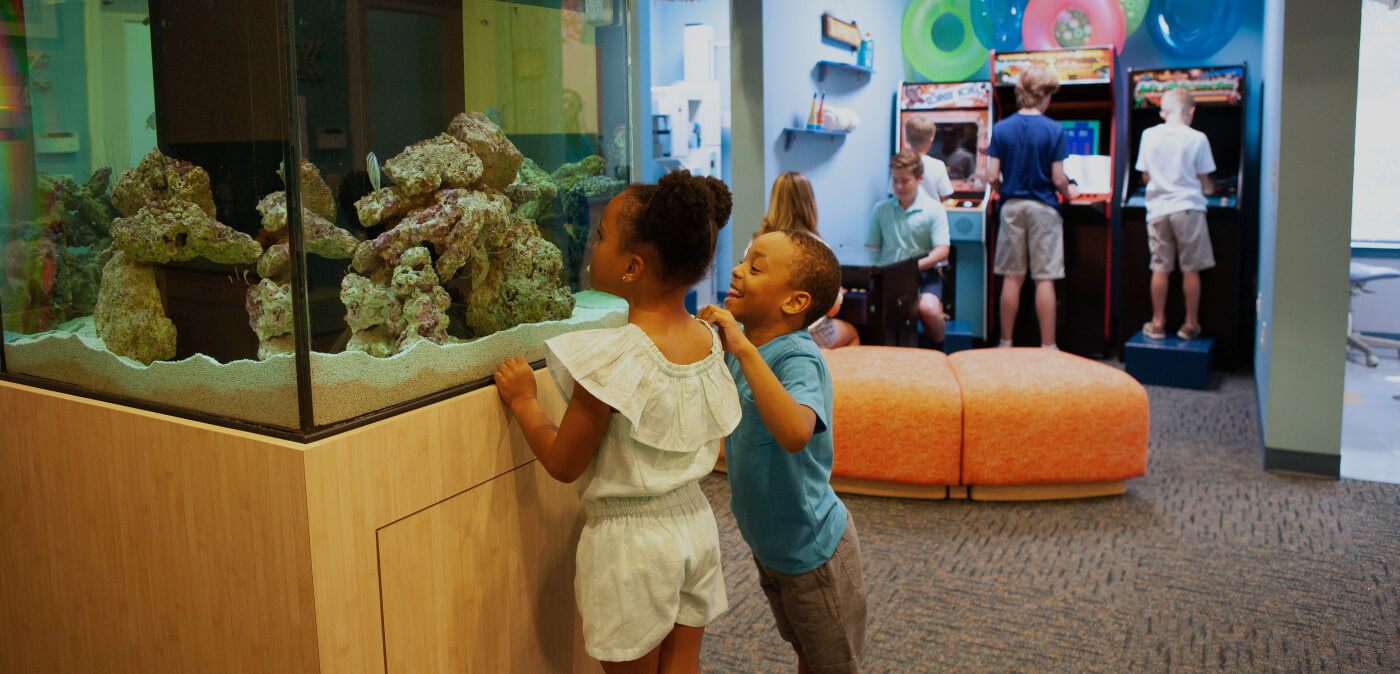 Group of kids enjoying fun waiting room activities like video games and looking at fish