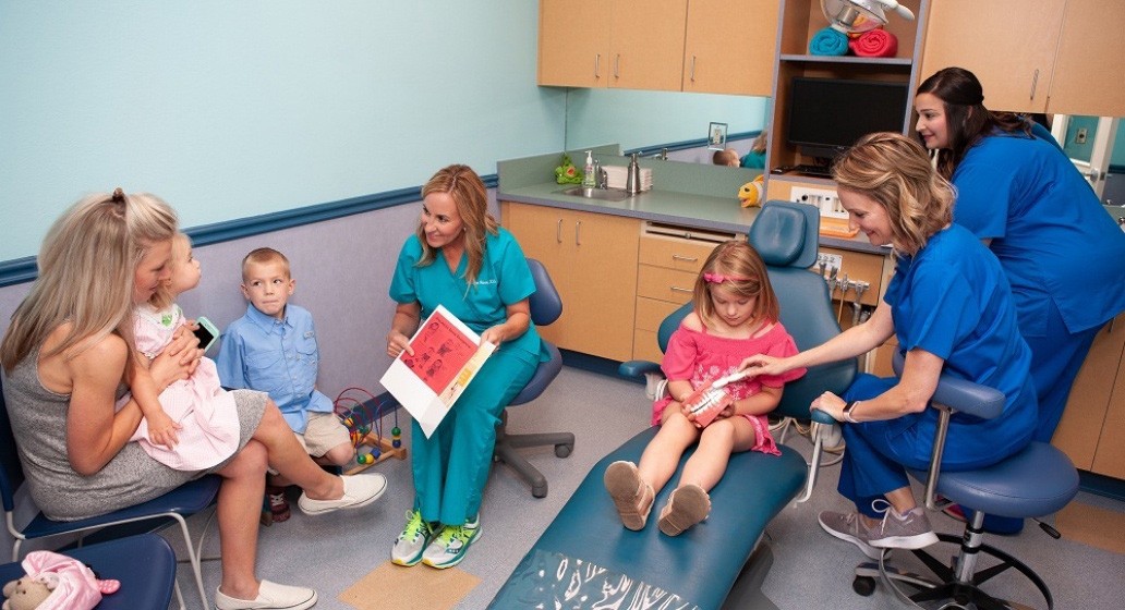 Dentist kids and parents in pediatric dental treatment room