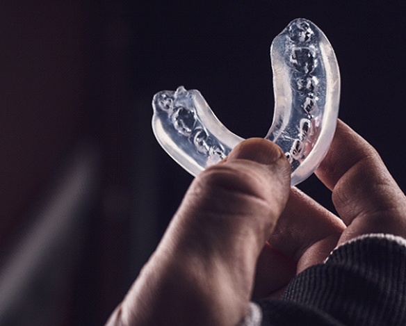 A person holding a custom-made sportsguard to show off the tooth indentations 