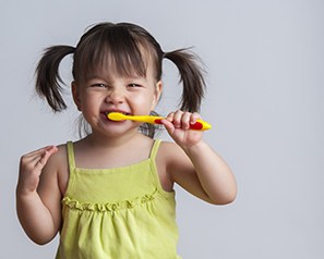 Smiling girl brushing her teeth to avoid children’s dental emergency in Coppell 