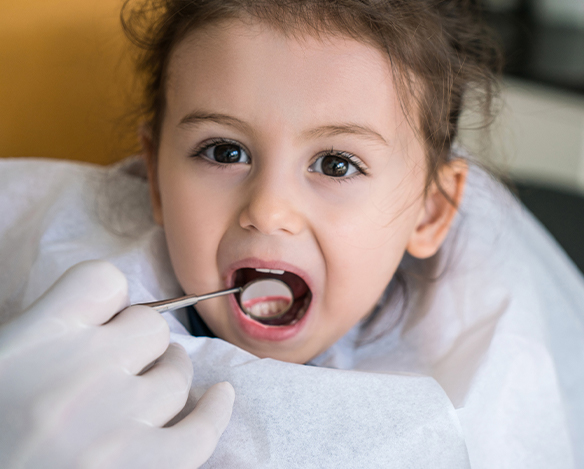 Dentist checking child's tooth-colored fillings during restorative dentistry visit