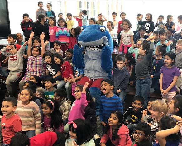 Large group of school kids posing with Sammy the Shark mascot