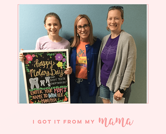 Dentist and two patients smiling and holding a sign