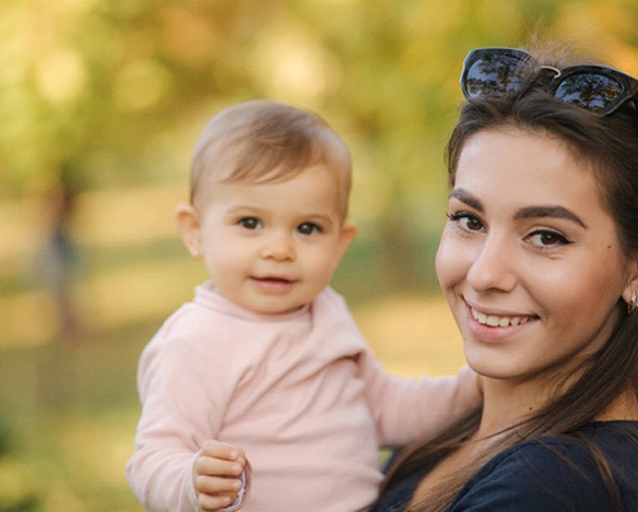 A mother and her teething baby in Coppell Texas standing outside and smiling