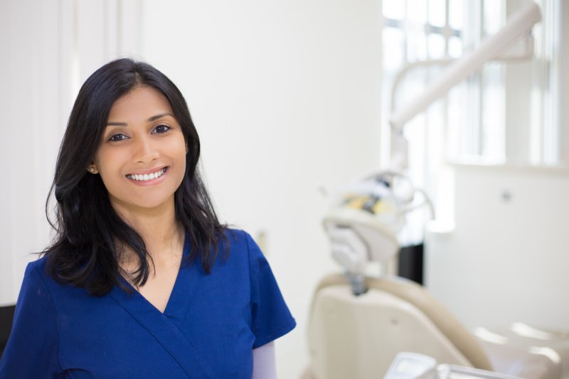 a dental professional wearing blue scrubs while in a treatment room