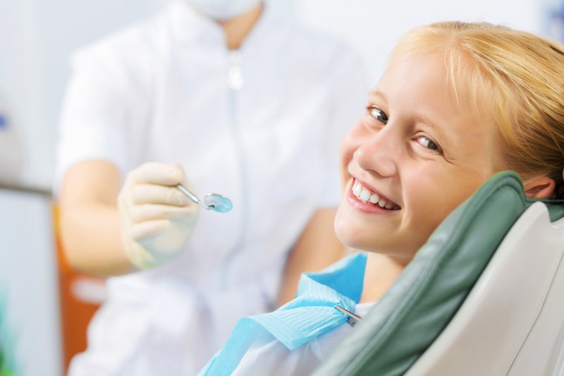 a little girl sitting and smiling in preparation for a dental checkup