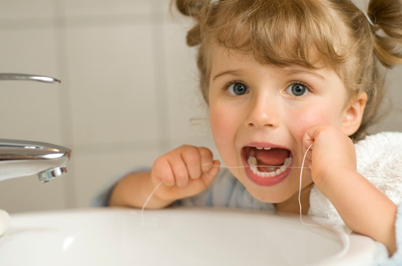 young girl flossing in bathroom